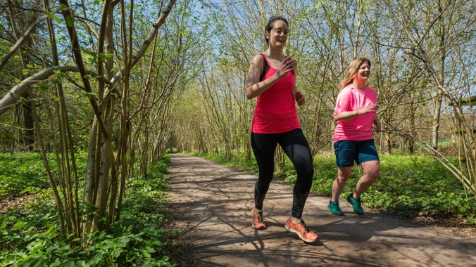 Two women running along a path in the woodland